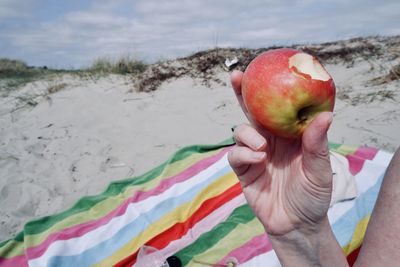 Hand holding apple on beach