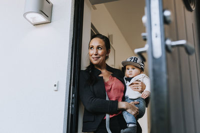 Portrait of happy boy standing against door