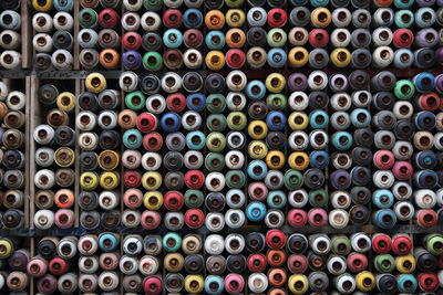 Full frame shot of multi colored aerosol cans