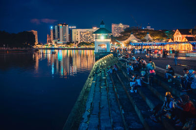 People on illuminated buildings in city at night