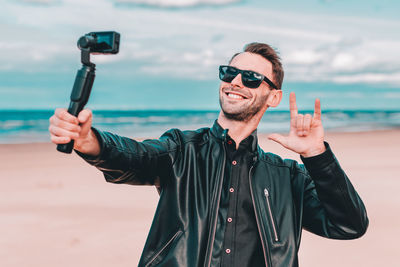 Smiling man filming video camera at beach