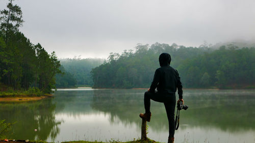 Rear view of man looking at lake against sky