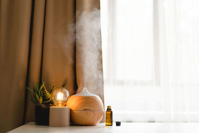 Aromatherapy concept. aroma oil diffuser on the table against the window.