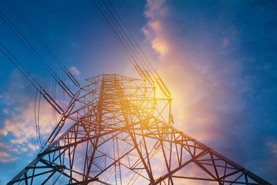 Low angle view of electricity pylon against sky during sunset