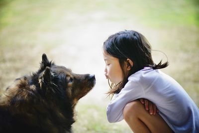 Side view of girl kissing dog