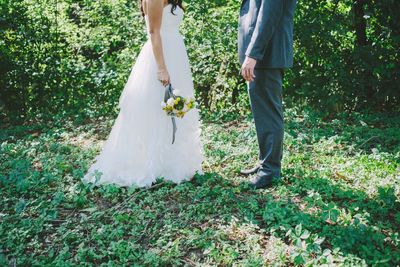 Low section of couple standing on field during wedding