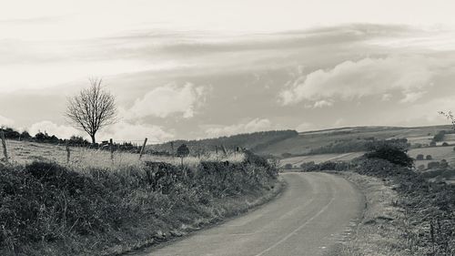 Road amidst field against sky