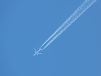 Low angle view of vapor trails against clear blue sky