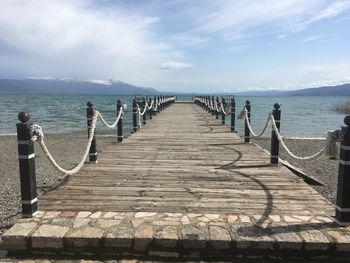 Wooden pier over sea against sky