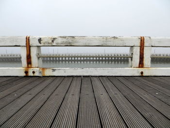 Fence by river against clear sky