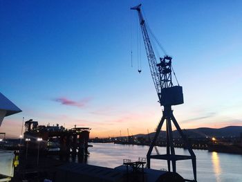 Cranes against sky at sunset