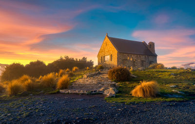 House on field against sky during sunset