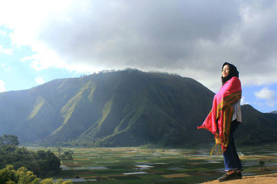 Woman standing on mountain against sky
