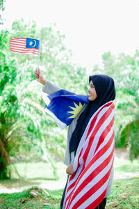 Muslim woman happy holding a malaysian flag. malaysia independence day.