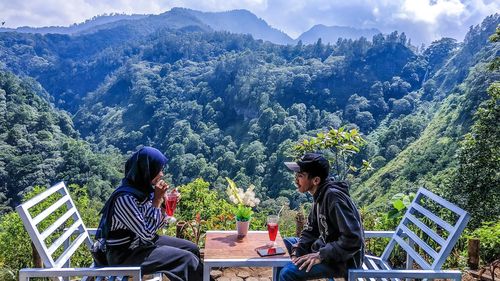 People sitting at park against mountains