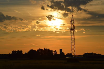 Electricity pylon on landscape against sunset