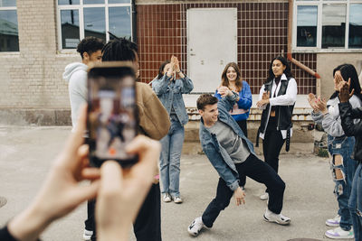 Multiracial men and women applauding while friend dancing on street