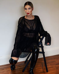 Portrait of beautiful young woman lying on hardwood floor against wall at home