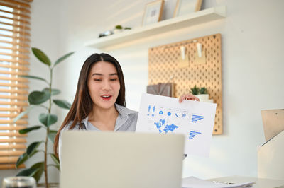 Portrait of young woman using laptop at home