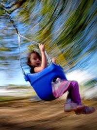 Blurred motion of girl sitting on swing in playground