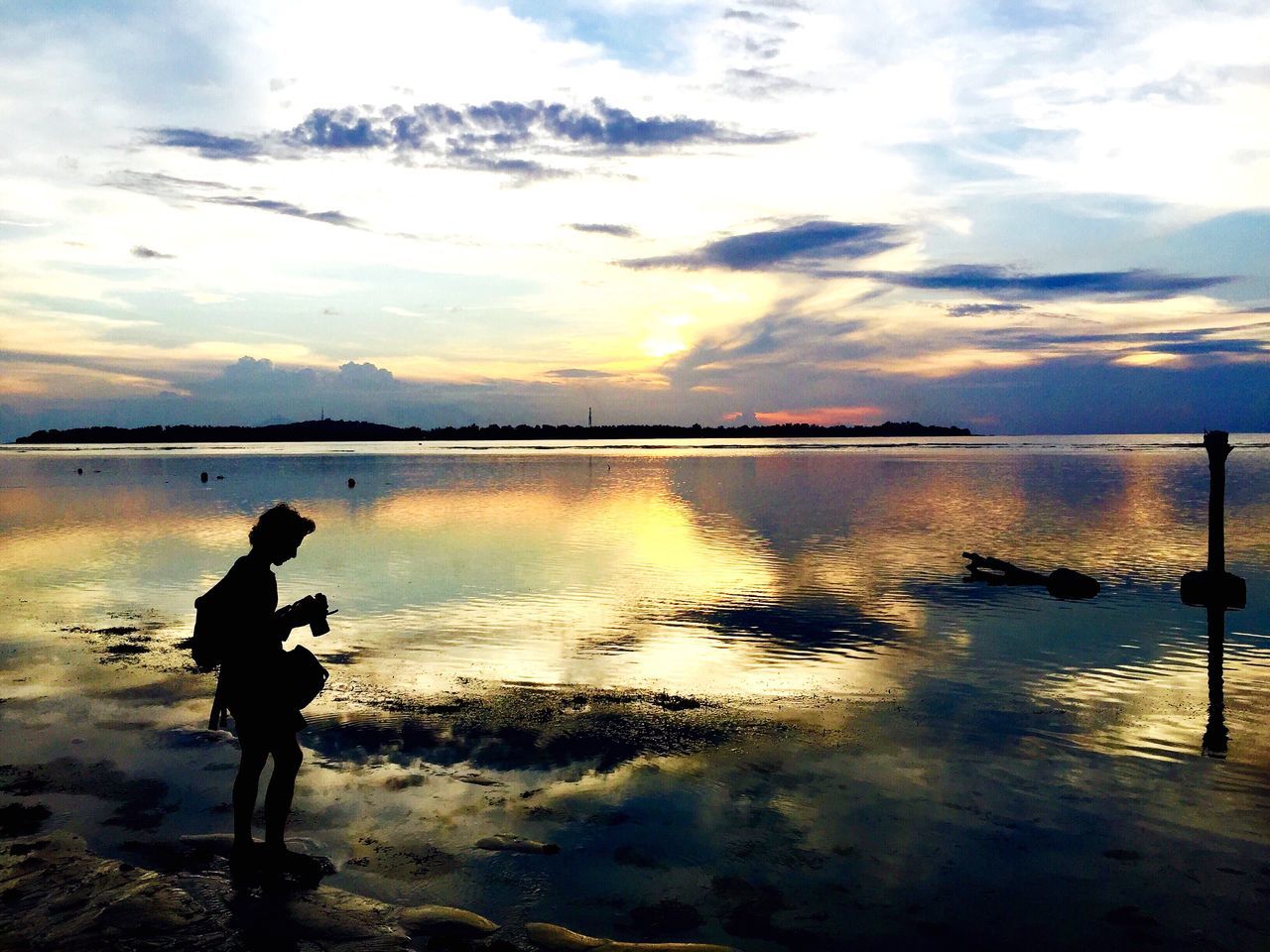 water, sunset, sky, silhouette, tranquility, scenics, tranquil scene, cloud - sky, beauty in nature, sea, reflection, standing, beach, leisure activity, nature, lifestyles, shore, men, lake