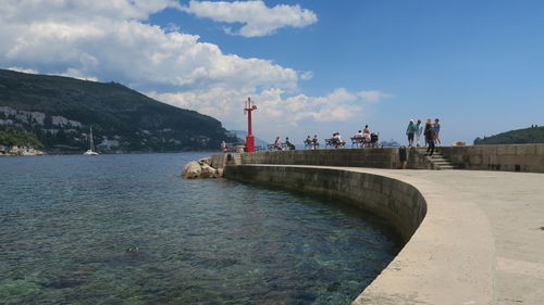 Walkway by lake against sky