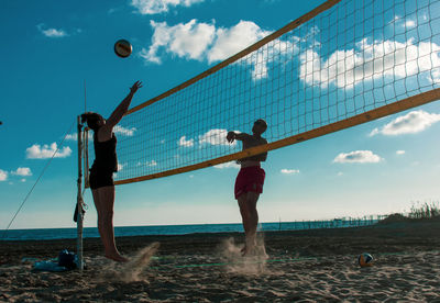 People playing beach volleyball against sky