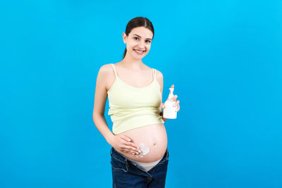 Portrait of a smiling young woman against blue background