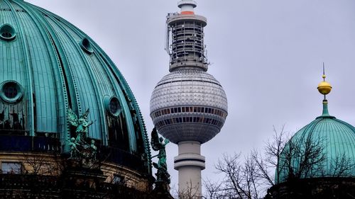 Tv tower between a church in the foreground