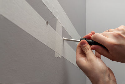 Midsection of person holding paper against wall