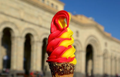 Yellow pineapple with red raspberry flavored soft serve ice cream cone against vintage building