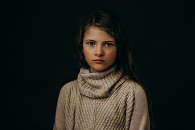 Close-up portrait of cute girl against black background