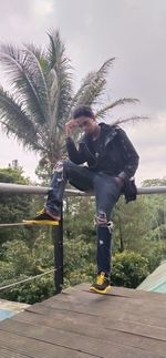 Side view of man standing by plants against sky