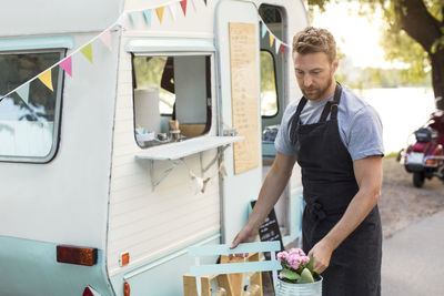 Male owner arranging table outside food truck on street