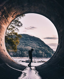 Silhouette man standing by water against sky