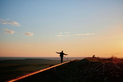 Rear view of man walking on pipe against landscape