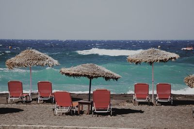 Lounge chairs and parasols at beach against clear sky