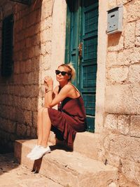 Portrait of young woman sitting on wall