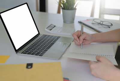 Midsection of man using laptop on table