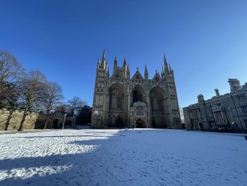 Church by building against clear blue sky during winter