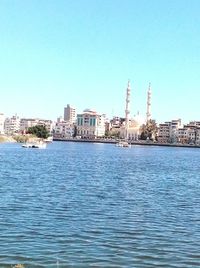 Sea by buildings against clear blue sky