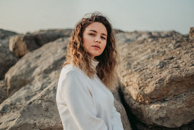 Portrait of beautiful young woman standing on rock