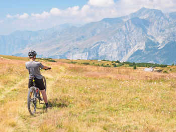 Cyclist boy stand on high hill against blue alps massive and enjoy sunset. mountain biking concept