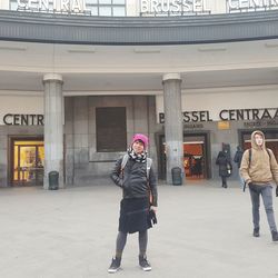 Full length of friends standing against wall in city
