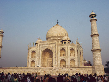 People at taj mahal against clear sky during sunset