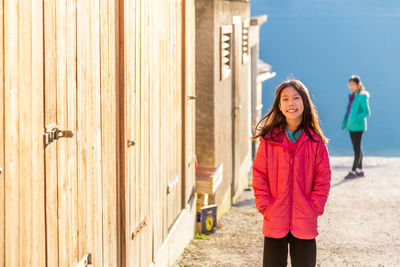 Two happy young asian girls standing back lit with morning sunrise and smiling at camera