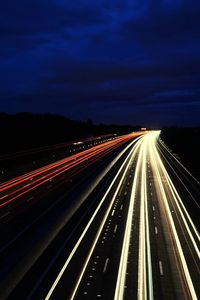 Light trails on road against sky at night