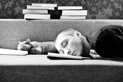 Man and cat sleeping on book at sofa