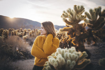 Woman standing by tree against sky during winter