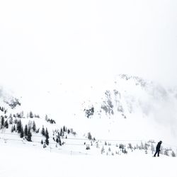 People on snow covered landscape against clear sky